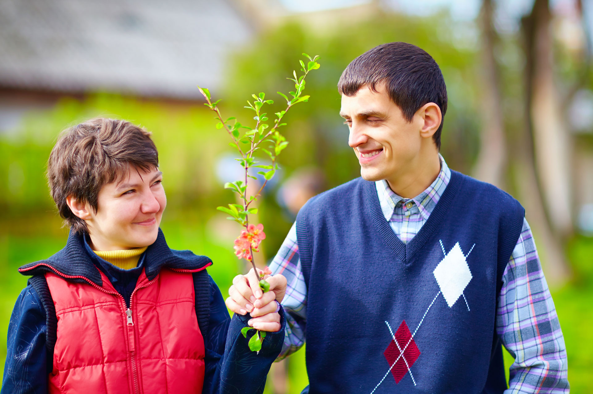 male and female adults with special needs holding a flower