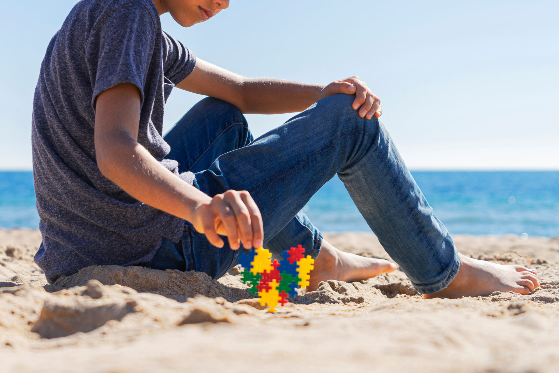 autistic boy on the beach with a puzzle heart