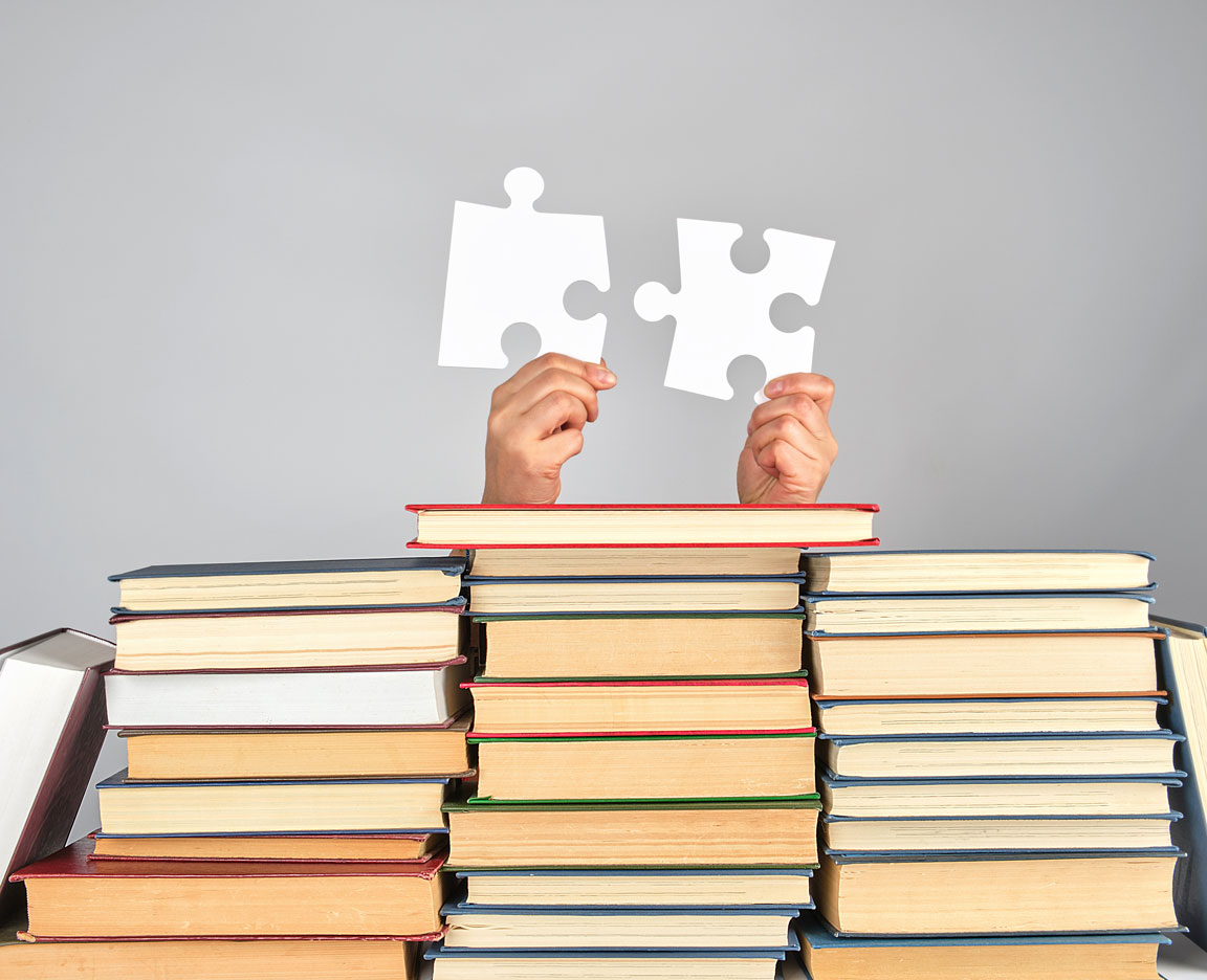 autism puzzle pieces being held above stacks of books