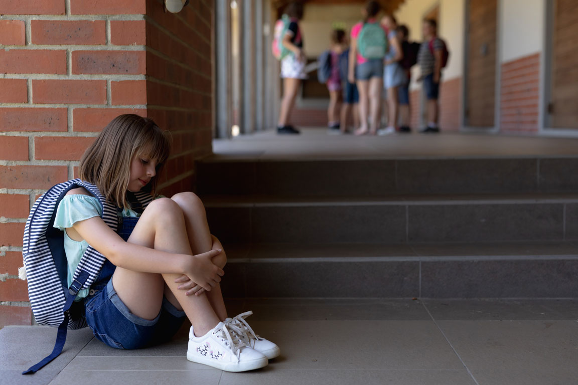 schoolgirl sitting on the ground upset