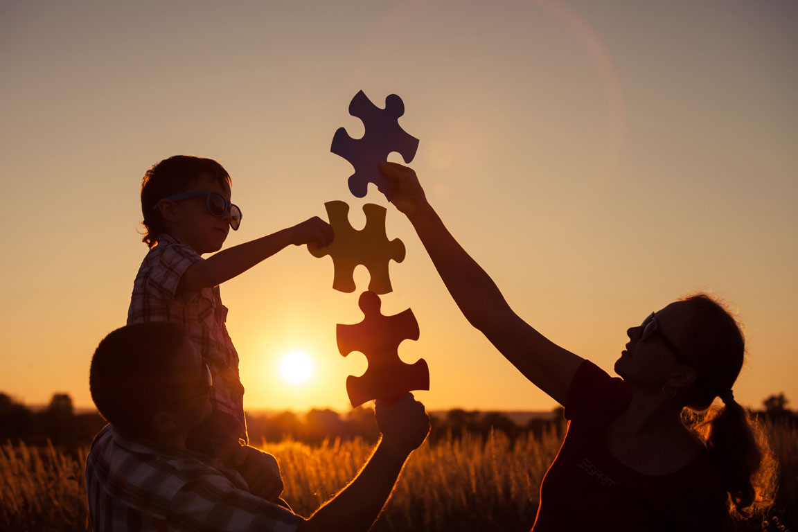 family holding giant puzzle pieces in the sunset
